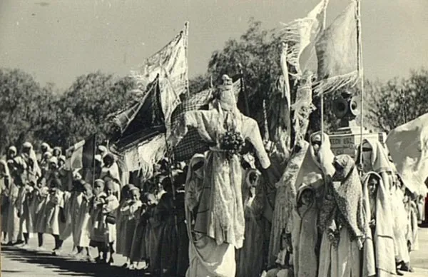 Hands preparing a decorated Taghonja figure for a rain ritual